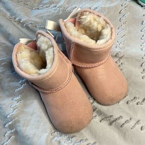 Uggs. infant boot. pink with white bow on back.